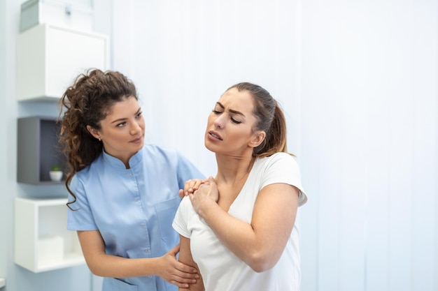 Mulher médica osteopata em uniforme médico consertando pacientes mulheres ombro e articulações nas costas na clínica de terapia manual durante a visita Osteopata profissional durante o trabalho com o conceito de paciente