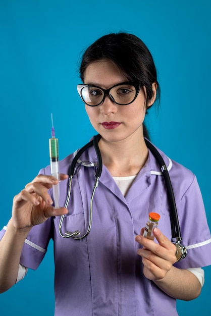 Mulher médica ou enfermeira em uniforme médico branco e luvas com seringa nas mãos isoladas