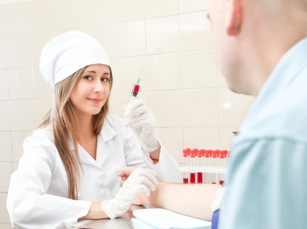 Mulher médica tira o sangue do paciente