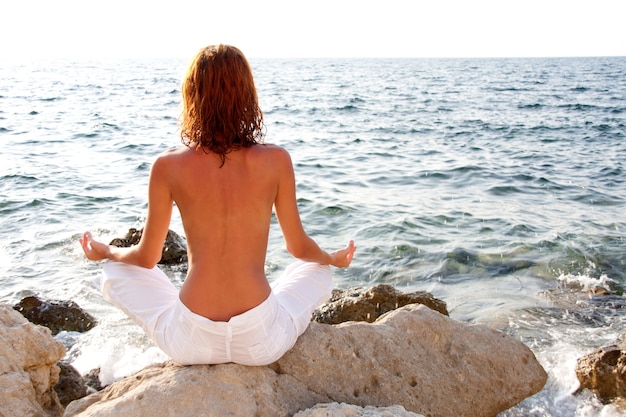 Mulher meditando contra o mar