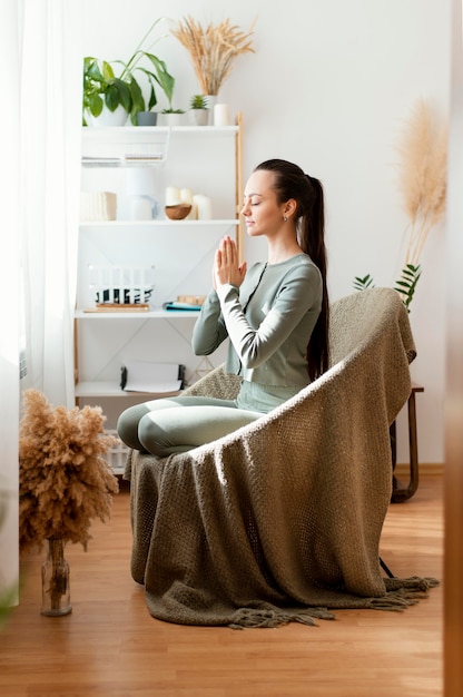 Mulher meditando em casa na cadeira