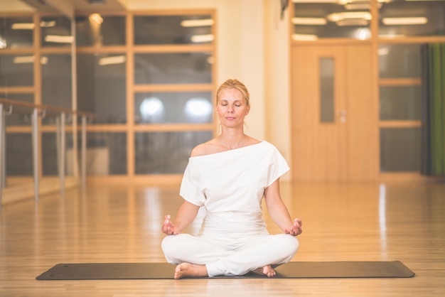 Mulher meditando, em, um, muktasana, ioga posa, em, estúdio