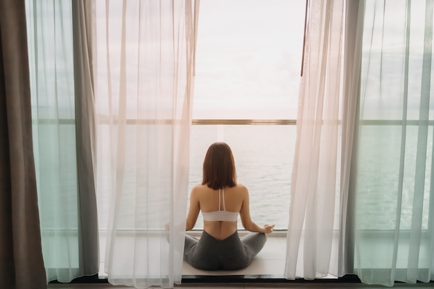 Mulher meditando ioga asana na varanda pela manhã