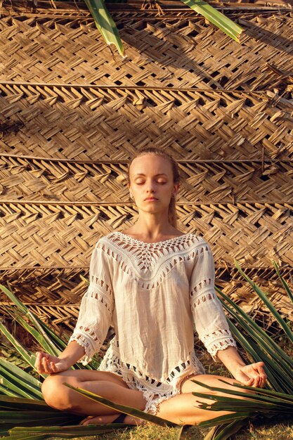 Mulher meditando sobre uma folha de palmeira