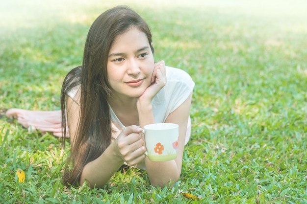 Mulher, mentindo, ligado, capim, campo, com, um, xícara café, parque