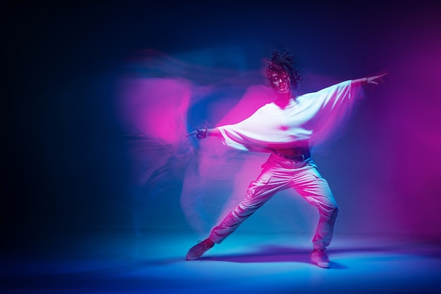 Mulher mestiça dançando em foto colorida de estúdio com luz de néon expressiva de longa exposição