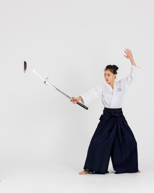 Mulher mestre de Aikido no quimono tradicional samurai hakama com faixa preta com espada katana no fundo branco Estilo de vida saudável e conceito de esportes