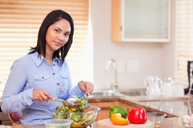 Foto mulher mexendo sua salada na cozinha