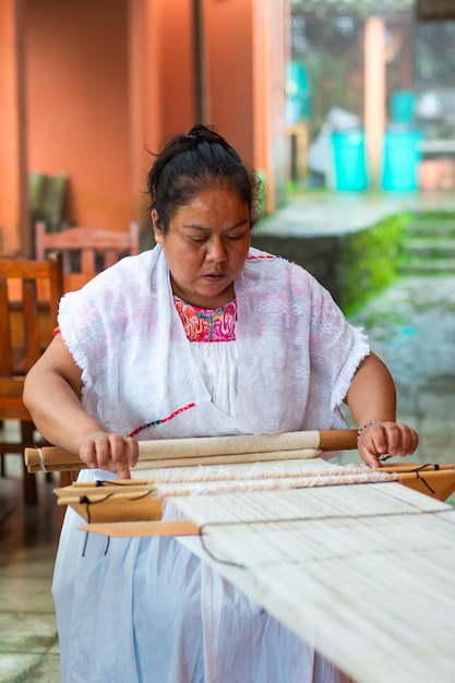 Mulher mexicana nativa adulta média usando um tear tradicional