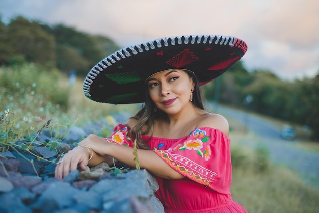 Mulher mexicana usando chapéu e vestido tradicional Retrato ao ar livre ao lado do muro de pedra