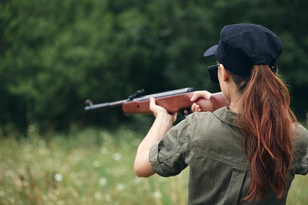 Mulher militar segurando uma arma de caça alvo vista traseira macacão verde vista recortada