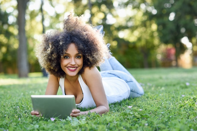 Mulher mista com penteado afro olhando para o tablet