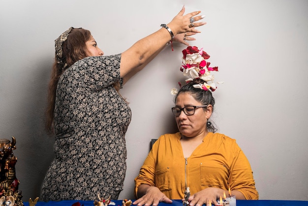 Foto mulher mística fazendo um ritual pagão colocando pétalas na cabeça de outra mulher