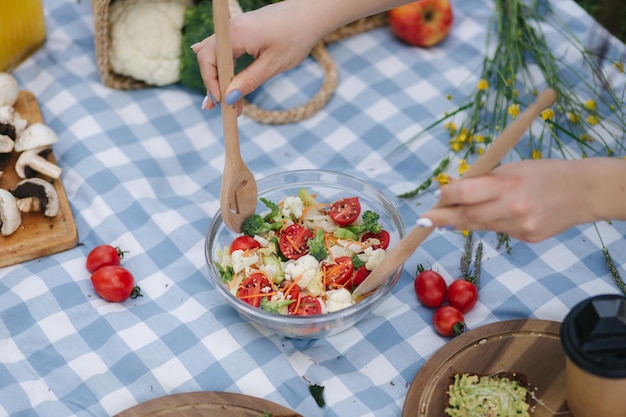 Mulher mistura salada vegana em piquenique fora do conceito de comida vegana