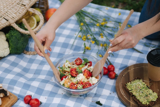 Mulher mistura salada vegana em piquenique fora do conceito de comida vegana