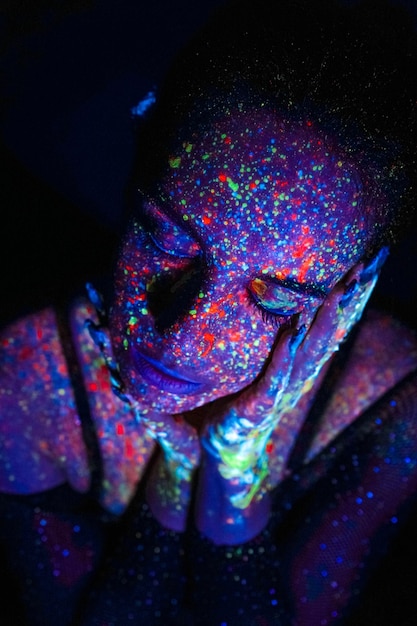 Foto mulher modelo em luz neon linda modelo menina com design de arte de maquiagem fluorescente de dançarina de discoteca dançando em luz uv maquiagem colorida festa de boate