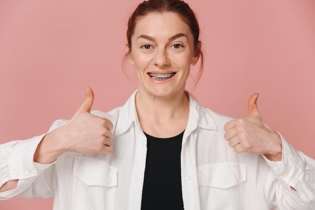 Mulher moderna feliz mostrando bem com as mãos em fundo rosa