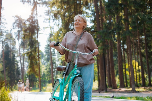 Mulher moderna idosa mais velha anda de bicicleta em um parque da cidade na floresta Estilo de vida ativo de aposentado