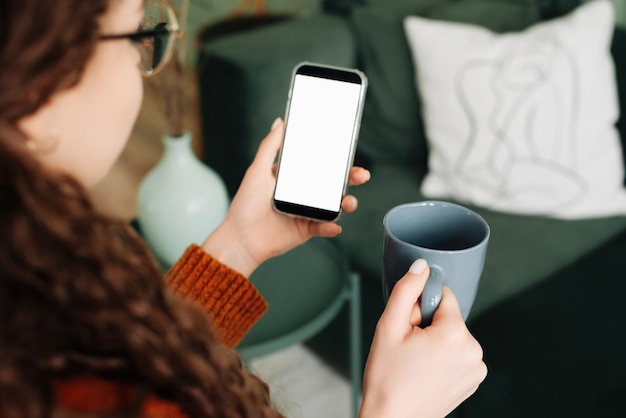 Mulher moderna usando smartphone e café com tela de maquete branca para maquete de publicidade