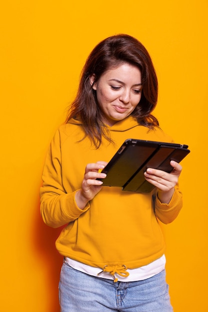 Mulher moderna usando tablet digital com tela de toque na câmera. Pessoa alegre segurando gadget moderno e olhando para exibição para trabalhar na conexão de internet online. adulto com dispositivo