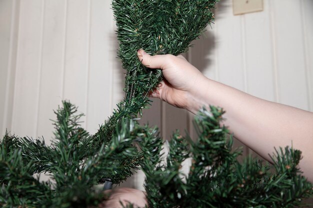 Mulher moldando os membros de uma árvore de Natal verde artificial