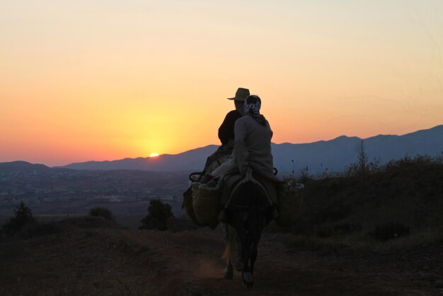 Foto mulher montando um cavalo na paisagem durante o pôr do sol