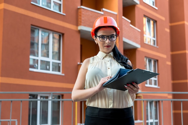 Mulher morena atraente calculando algo no canteiro de obras