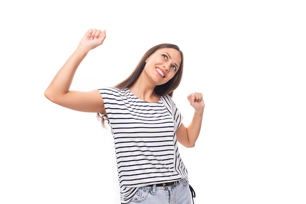 Mulher morena caucasiana alegre e enérgica em uma camiseta listrada sorrindo em um fundo branco