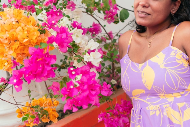 Mulher morena com roupas da moda, posando na rua e sorrindo.