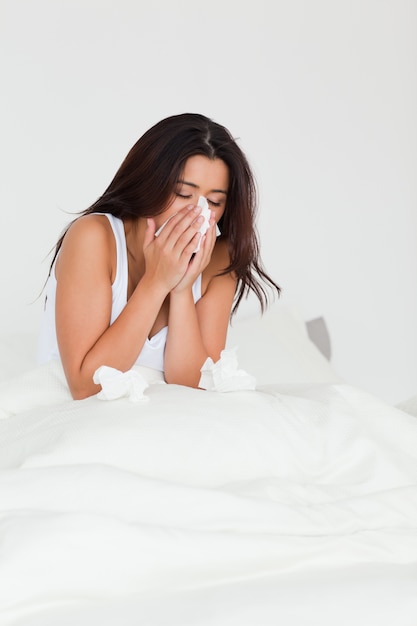 Mulher morena com um frio sentado na cama