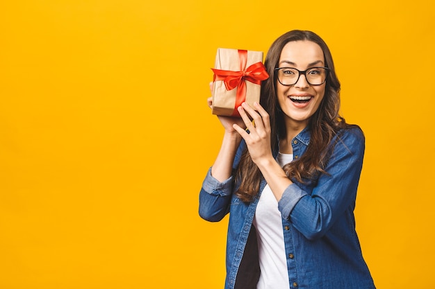 Mulher morena feliz casual segurando uma caixa de presente