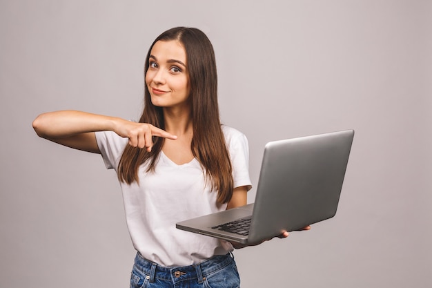 Mulher morena feliz e surpresa mostrando a tela do laptop em branco