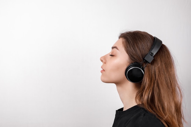 Mulher morena feliz sorrindo ouvindo música com fones de ouvido em um espaço em branco isolado