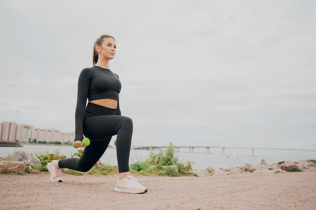 Mulher morena fitness fazendo alongamento corporal fazendo esportes ao ar livre Um atleta em um apertado