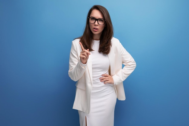 Mulher morena indignada em vestido branco no fundo do estúdio