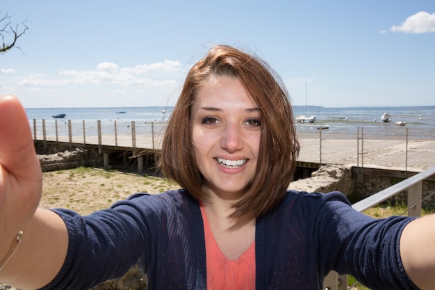 Mulher morena na praia fazendo uma selfie