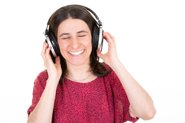 Mulher morena ouvindo música com garota de fones de ouvido posando isolada no retrato de estúdio de fundo de parede branca