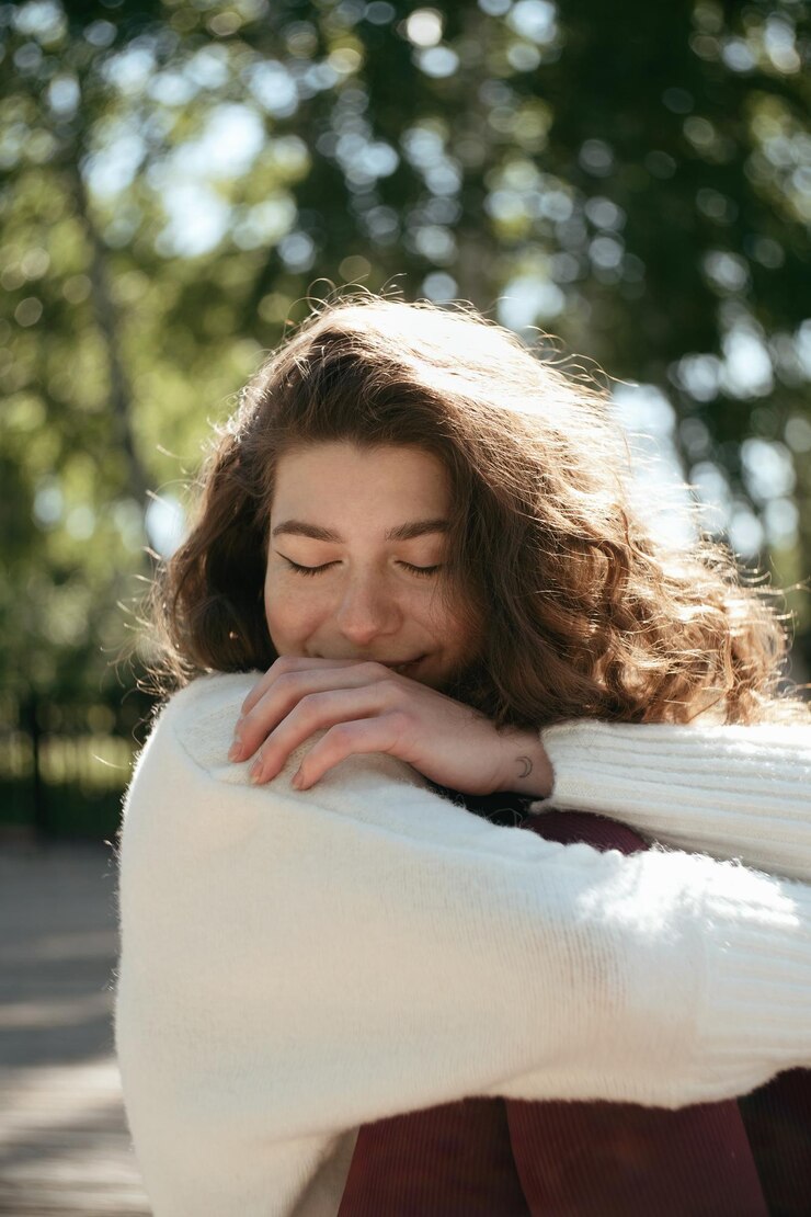 Foto mulher morena sorridente de olhos fechados sentada no parque