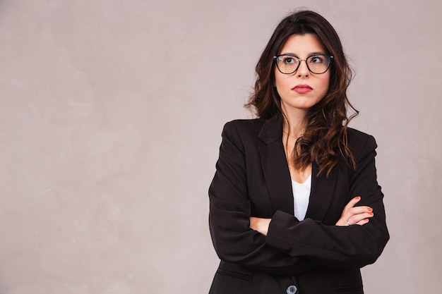 Mulher morena sorridente sem óculos, posando com os braços cruzados e olhando para a câmera.