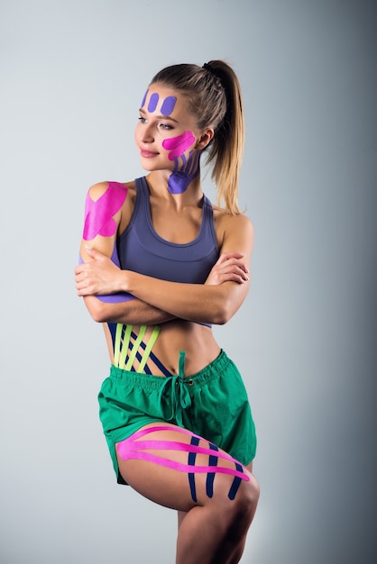 Mulher mostra fitas de kinesio coladas em seu corpo. Esporte e conceito de estilo de vida saudável