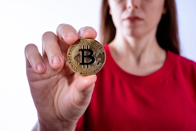 Mulher mostrando moeda física de metal Bitcoin (BTC). Gravação de estúdio.