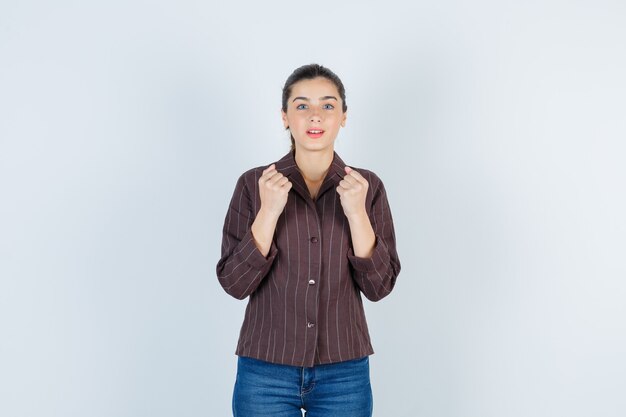 Mulher mostrando o gesto de vencedor em camiseta, jeans e parecendo com sorte. vista frontal.