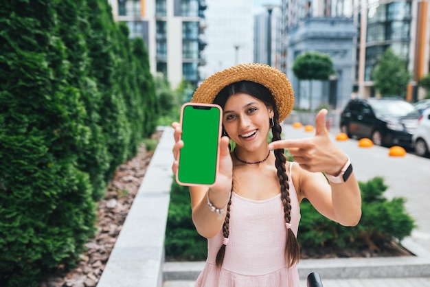 Mulher mostrando smartphone moderno com tela verde para substituição