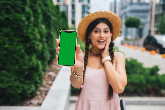 Mulher mostrando smartphone moderno com tela verde para substituição