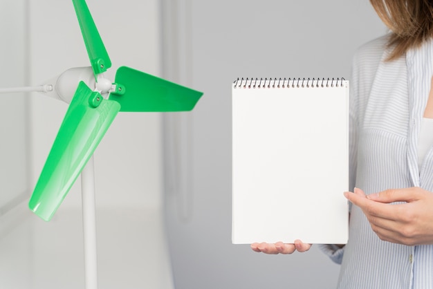 Foto mulher mostrando um caderno em branco para uma inovação em energia eólica