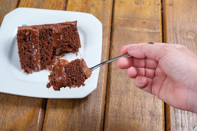 Mulher mostrando um pedaço de bolo de chocolate com recheio de ganache de chocolate meio amargo