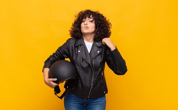 Mulher motociclista parecendo arrogante, bem-sucedida, positiva e orgulhosa, apontando para si mesma