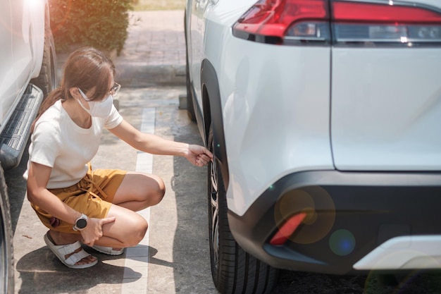 Mulher motorista inflando os pneus do veículo removendo a tampa de nitrogênio da válvula do pneu para verificar a pressão do ar e encher o ar na roda do carro na manutenção e segurança do autoatendimento do posto de gasolina