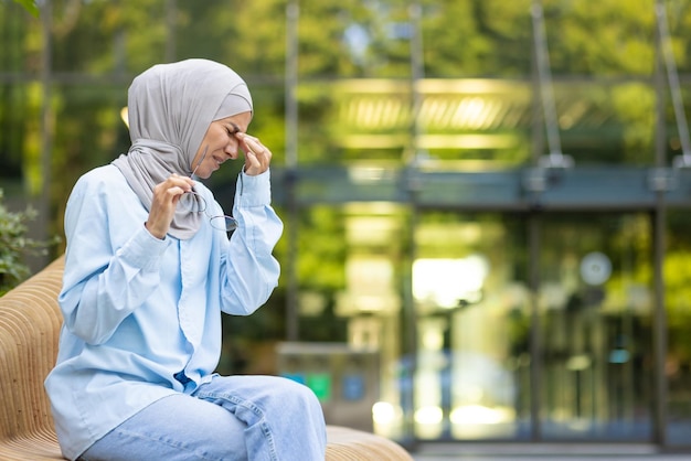 Mulher muçulmana adulta de hijab azul com dor de cabeça severa ou enxaqueca segurando a cabeça em dor enquanto