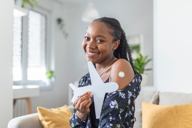 Mulher muçulmana africana sorrindo depois de receber uma vacina segurando um avião de papel como um símbolo de pronto para viajar Mulher mostrando seu braço com bandagem depois de receber a vacina